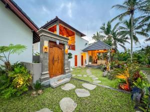 a house with a garden and a wooden door at Ascarya Villa Ubud in Ubud