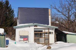 a small white house with a black roof at オホーツクハウスえんがる in Engaru
