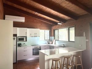 a kitchen with white cabinets and bar stools at For Rest at Crescent Head in Crescent Head