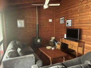 a living room with a couch and a flat screen tv at For Rest at Crescent Head in Crescent Head