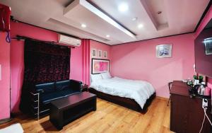 a bedroom with pink walls and a bed and a desk at 필모텔 in Yeoju