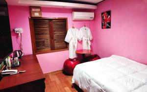 a bedroom with pink walls and a bed and a desk at 필모텔 in Yeoju
