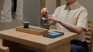 a woman is standing next to a table with a tea kettle at Anook Ryokan Hotel Eunpyeong Bulgwang in Seoul