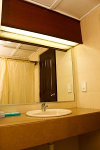 lavabo en el baño con un espejo grande encima. en De Rhu Beach Resort, en Kuantan
