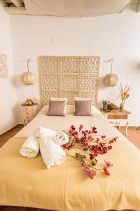 a bedroom with a bed with towels and flowers on it at Casa Bodega Triana in Vejer de la Frontera