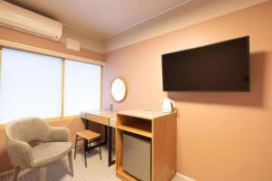 a hotel room with a flat screen tv on the wall at B cycle シングルルーム in Biei