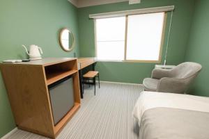 a bedroom with a desk and a bed and a window at B cycle シングルルーム in Biei