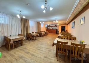a restaurant with tables and chairs in a room at Hotel Nurlytau in Borovoye
