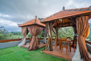a wooden gazebo with chairs and a table on a roof at DWM Mandhasativa Homestay By Reccoma in Singaraja