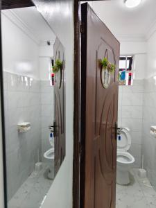 a bathroom with two toilets and a wooden door at Fan Farm Stay in Munyu