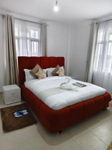 a large red bed in a room with windows at Fan Farm Stay in Munyu