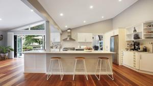 a kitchen with white cabinets and a island with bar stools at Arcadia Cottage in Bowral