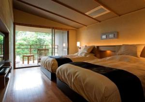 a hotel room with two beds and a balcony at Oyado The Earth in Toba