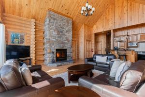 a living room with leather furniture and a stone fireplace at Fiddler Lake Resort - Deer 73 in Mille-Isles