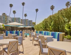 a patio with tables and chairs and palm trees at Hyatt Centric Delfina Santa Monica in Los Angeles