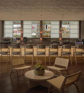 a restaurant with chairs and a bar in the background at Hyatt Centric Delfina Santa Monica in Los Angeles