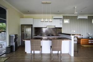 a kitchen with white cabinets and a counter with chairs at Kimana Villa in Manggis