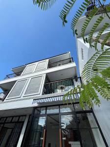 a tall white building with windows and some leaves at Mersey Residence Koh Samui in Lamai +16 photos