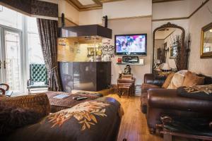 a living room with leather furniture and a tv at The Leicester in Southport