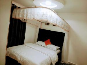 a bedroom with a white bed with a window at HomePlug Realty in Ongata Rongai 