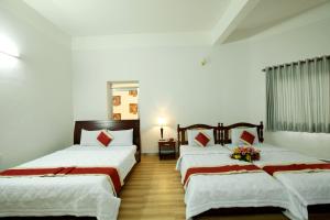 Habitación con 2 camas, paredes blancas y suelo de madera. en Tan Da Hotel, en Ho Chi Minh