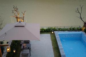 a swimming pool with a white umbrella and a swimming pool at Anvi Haven in Sóc Sơn