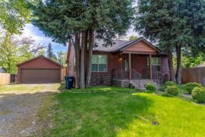 a brown house with a fence and trees at The Hangout House With Bonus Game Room & Foosball in Coeur d'Alene