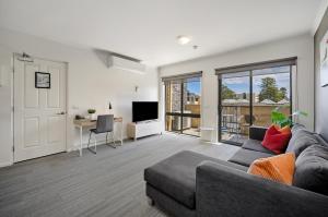 a living room with a couch and a tv at Quest Warrnambool in Warrnambool