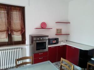 a kitchen with red cabinets and a clock on the wall at Alloggio per 4 persone con due camere da letto e cucina in Carrù
