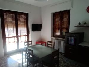 a dining room with a table and chairs and two windows at Alloggio per 4 persone con due camere da letto e cucina in Carrù
