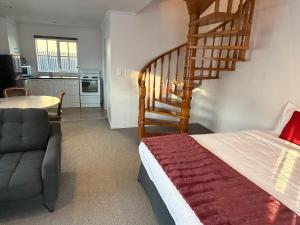 a bedroom with a staircase and a bed and a chair at Settlers Motor Lodge in Lower Hutt