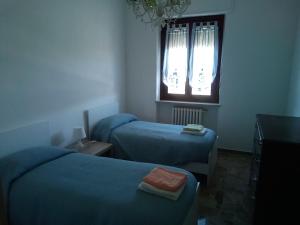 a room with two beds and a window and a table at Alloggio per 4 persone con due camere da letto e cucina in Carrù