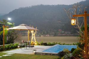 a swimming pool with an umbrella and a view of a river at Anvi Haven in Sóc Sơn +2 photos