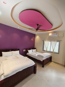 a bedroom with two beds and a purple wall at NARGILA HAMPi in Hampi +19 photos
