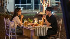 a man and a woman sitting at a table with food at Chaesonghwa Glamping in Yeongcheon in Yeongcheon
