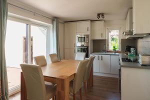 a kitchen with a wooden table and white cabinets at Driftwood in Croyde