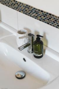 a bathroom sink with a bottle of mouthwash and a soap dispenser at Driftwood in Croyde +17 photos