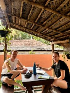 two people sitting at a table under a roof at Social Stays in Negombo