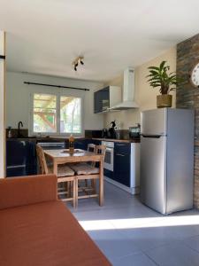 a kitchen with a stainless steel refrigerator and a table at Gîte la pause en baie in Pendé