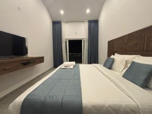 a bedroom with a large bed and a flat screen tv at Kodai Square Homestay in Kodaikānāl