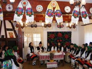 een groep mensen die aan een tafel in een kamer zitten bij Pensiunea Sanziene in Strîmtura