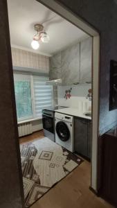 a kitchen with a stove and a dishwasher at Апартамент возле аэропорта in Almaty +1 photo
