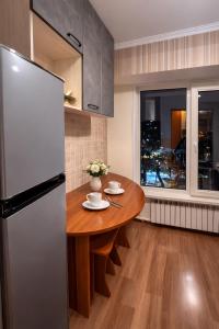 a kitchen with a wooden table and a refrigerator at Апартамент возле аэропорта in Almaty