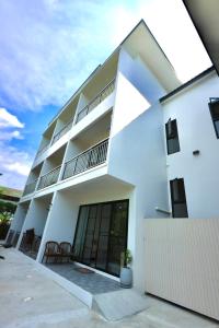 a white apartment building with a balcony at KL Dawarika Mali Hotel in Ban Tai