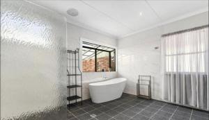 a white bathroom with a tub and a window at The Haven House in Singleton +20 photos