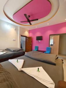 two beds in a room with a pink ceiling at NARGILA HAMPi in Hampi