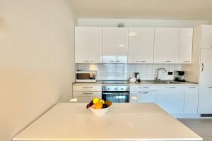 a kitchen with white cabinets and a bowl of fruit on a counter at Residence degli Oleandri 4B in Argegno +16 photos