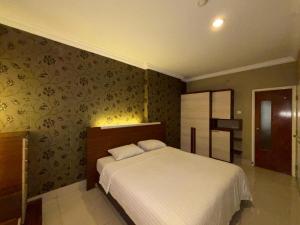 a bedroom with a bed and a wall with floral wallpaper at MTC Mega Mas Apartment in Manado