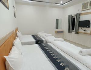 a hospital room with three beds and a tv at Hotel Assi Retreat in Varanasi