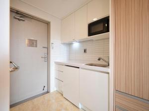 a kitchen with white cabinets and a sink and a door at Uljiro Coop Residence Dongdaemun in Seoul